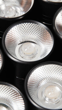 Close-up of multiple modern LED light bulbs with textured silver dimpled reflectors in a sleek black lighting fixture, showcasing advanced illumination technology vertical photo