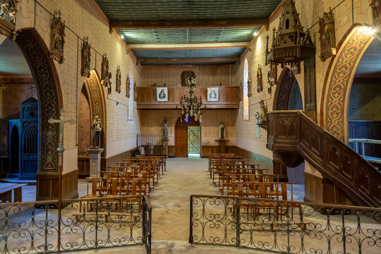 Wide view of a church nave with empty chairs and a wooden choir loft, Gers, Saint Georges, France
