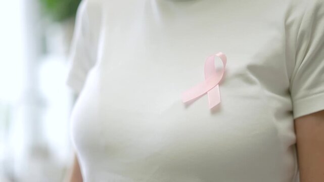 Resilient survivor woman stands confidently displaying pink ribbon symbol. This hopeful figure actively supports cause with determination.