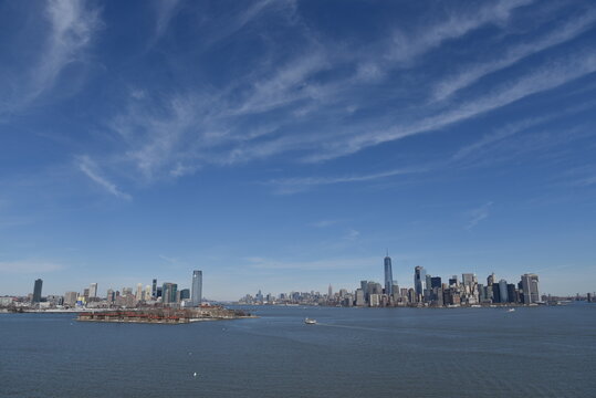 Panoramic view of Manhattan and Jersey City skylines across the Hudson River under a clear blue sky in New York City, USA