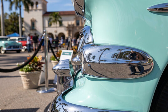 Classic car chrome bumper guard with turquoise paint at car show  