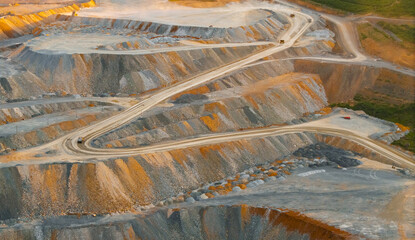 Obraz premium Open pit mine haul roads winding through terraced excavation, concept mining golden ore