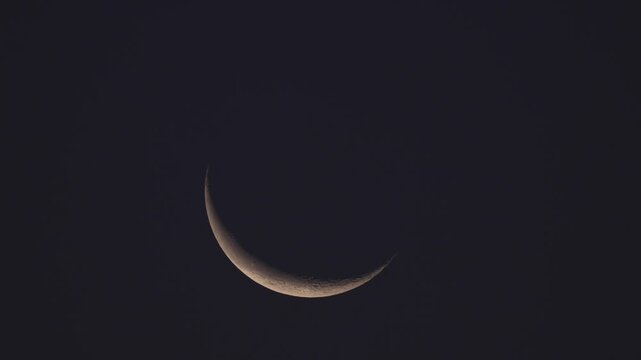 Minimalist shot of a delicate crescent moon glowing in the expansive sky