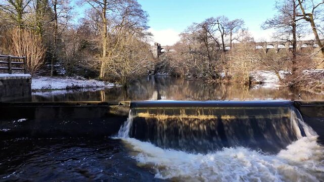 Scenic winter footage of Lake Vyrnwy reservoir in Wales, featuring snow-covered landscape, water, woodland and the historic dam and surrounding streams.