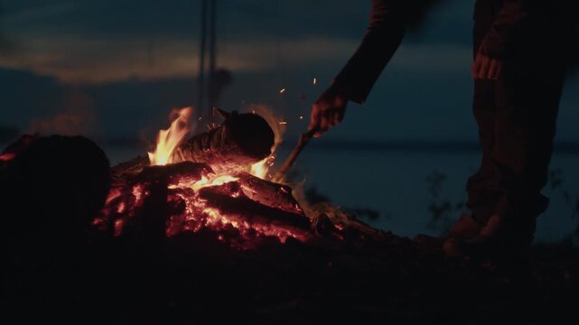 Sailing and camping in the wild. Woman sailor walks on the wild area with sailing boat on the background and bonfire on the foreground