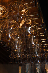 Close-up of clean wine glasses hanging upside down above a restaurant bar counter, showcasing elegant glassware and bar interior details © Liana