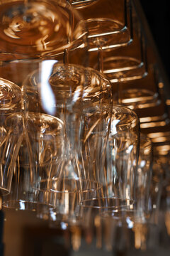 Close-up of clean wine glasses hanging upside down above a restaurant bar counter, showcasing elegant glassware and bar interior details