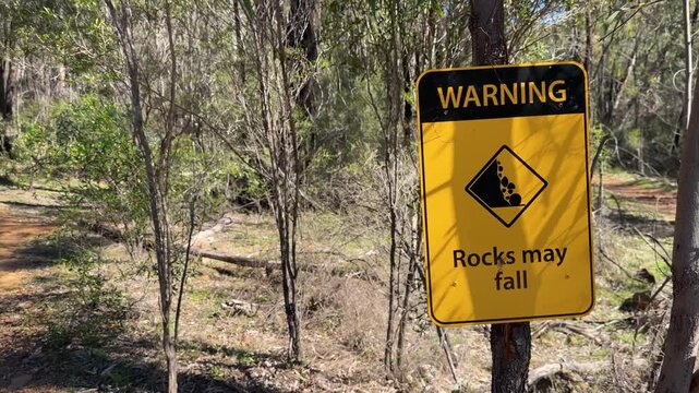 Yellow Falling Rocks Warning Sign Beside Australian Bushland Hiking Trail