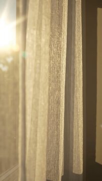 Sheer curtains softly illuminated by sunlight, creating a warm ambiance in a cozy indoor setting with visible textures and patterns enhancing the atmosphere