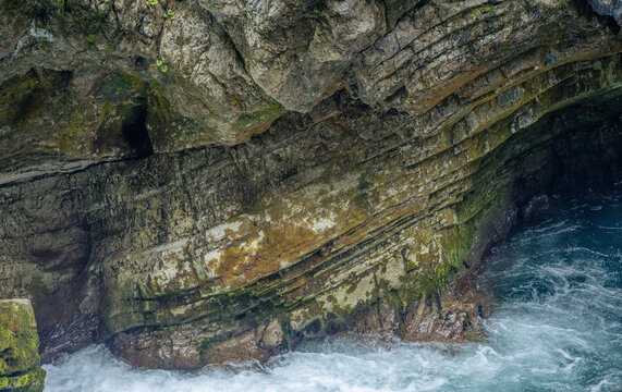 rocky sea cave entrance with textured stone walls and turbulent ocean water crashing inside