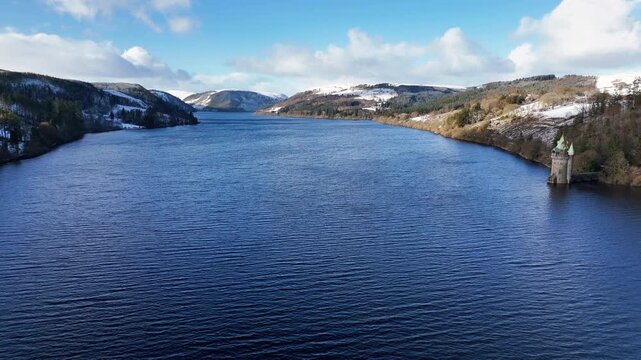 Scenic winter footage of Lake Vyrnwy reservoir in Wales, featuring snow-covered landscape, water, woodland and the historic dam and surrounding streams.