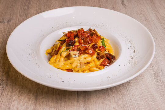 Piatto di pasta Carbonara con crema d'uovo, guanciale croccante, basilico e carciofi fritti servito come primo piatto in un ristorante 