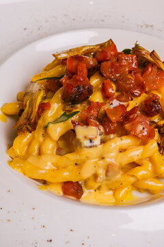 Piatto di pasta Carbonara con crema d'uovo, guanciale croccante, basilico e carciofi fritti servito come primo piatto in un ristorante 