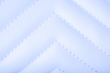Soft light blue quilted leather texture featuring white stitched chevron pattern background surface detail © reddish