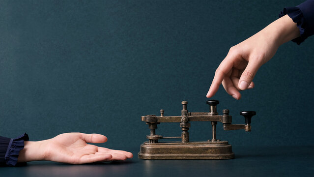 Hand tapping vintage Morse code key for telegraph communication and historical messaging