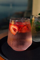 Obraz premium Strawberry lemonade with lime and fresh mint overlooking the sea at sunset 