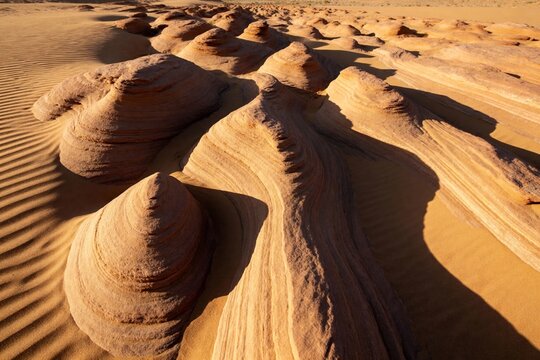 Sand formations in a desert landscape with wind-sculpted dunes and layered textures
