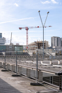 Urban construction site beside railway infrastructure with cranes tracks and modern buildings forming a layered redevelopment scene under a bright sky