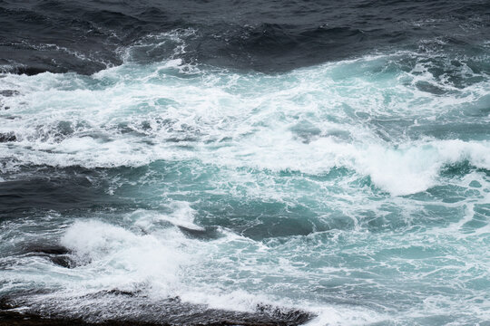 Rough ocean waves crashing against the rocky shores of Scotland