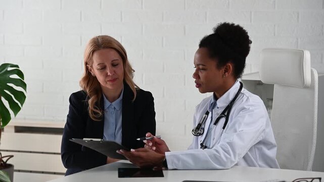 Doctor explaining test results and treatment options to female patient during consultation, helping her understand choices and make an informed healthcare decision