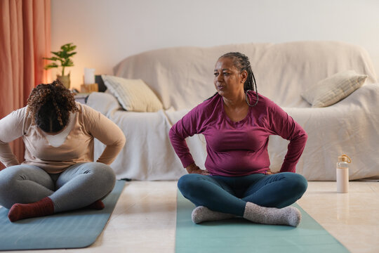 African mother and daughter doing yoga morning routine at home - Healthy lifestyle, family and body consciousness concept