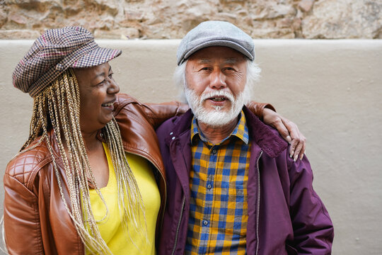 Happy multiracial senior couple having fun together during city trip - Autumn season, joyful elderly people and travel concept