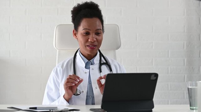 Friendly female physician speaking and listening to patient during virtual medical appointment. Warm professional communication in remote healthcare consultation
