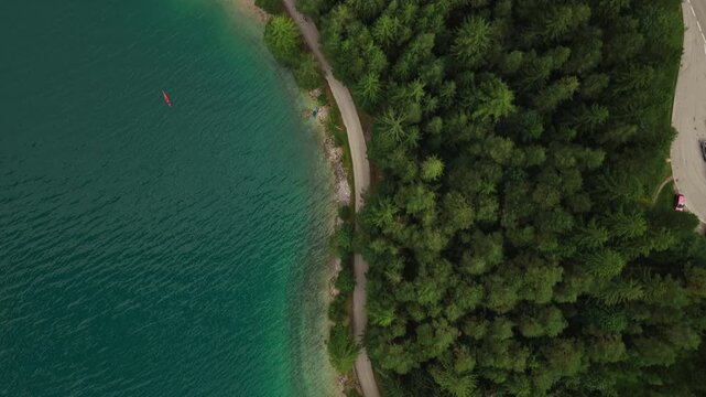 Blue waters of Lake Achensee in Tyrol, Austria, bordered by forested trees - drone top down