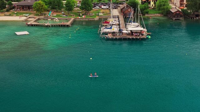 People paddleboarding and enjoying other recreational activities on Lake Achensee in Tyrol, Austria, surrounded by blue alpine water and mountain scenery - drone shot