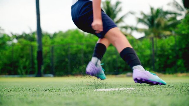 Kid boy leg kicking soccer ball on green grass field action. conceptual metaphor for youth sports training team competition fitness health wellness and active lifestyle	