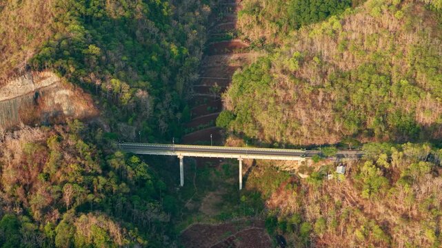Aerial view of a concrete bridge spanning a valley in the lush forested landscape of Gunungkidul Regency, Special Region of Yogyakarta, Indonesia.