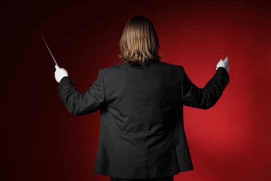 Male conductor on red background, back view