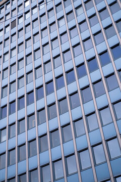 Blue glass office facade in Oslo Norway forms a clean geometric pattern of reflective windows in a modern corporate architecture detail