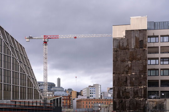 Urban redevelopment in Oslo Norway shows a construction crane and modern buildings beneath dramatic grey clouds in a changing city skyline
