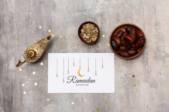 Greeting card, Aladdin lamp, dates and pumpkin seeds on grey grunge background. Ramadan celebration