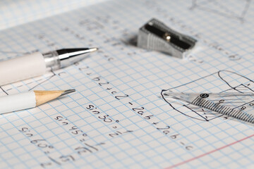 Fototapeta premium Copybook with handwritten maths formulas and stationery as background, closeup