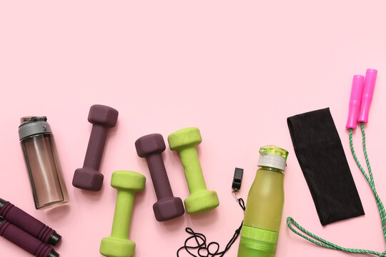 Headband, whistle and different sports equipment on pink background