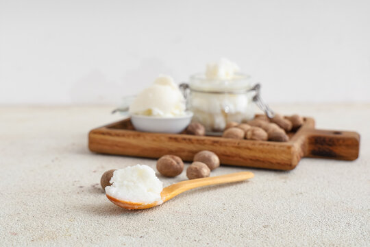 Wooden spoon with shea butter and nuts on light table