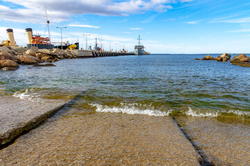 Low angle view of a small wave splashing on a concrete ramp inside Lennusadam Harbour in Tallinn, Estonia, with historic museum ships docked at the pier. © Vlad Rakin