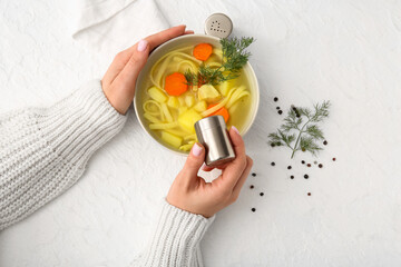 Obraz premium Woman adding spices into bowl with tasty chicken soup on white background