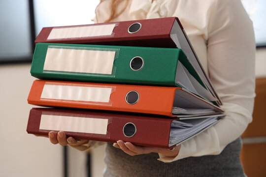 Young businesswoman with document folders in office, closeup