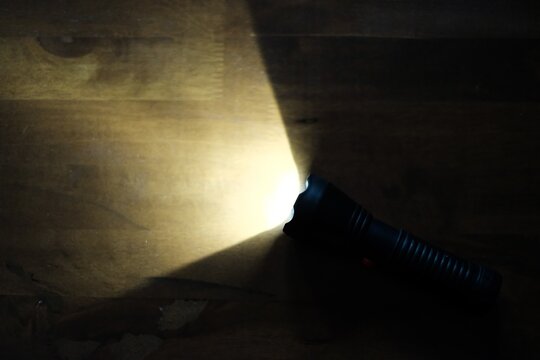 Bright flashlight beam illuminating a dark  surface in the dark. Concept of guidance, discovery, finding solutions, direction, inspection, and searching in darkness