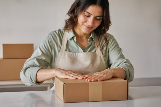 Entrepreneuse pr&eacute;parant un colis en carton recyclable