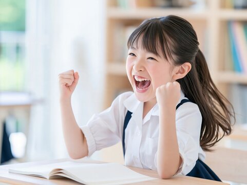 自分の部屋でテストの合格を喜び笑顔で両手を上げて大はしゃぎする女の子