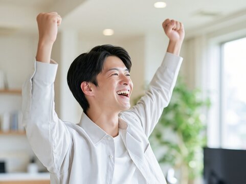 オフィスで拳を力強く握りしめ満面の笑みでガッツポーズをして喜ぶ男性