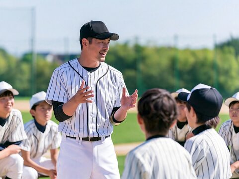 野球グランドでユニフォームを着て少年野球の指導を熱心に行う男性コーチ