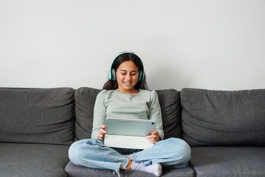 Female teen using tablet while drawing sitting on home sofa - Technology and teenager lifestyle concept - Main focus on face
