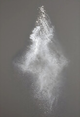 Obraz premium Explosion and motion concept white powder particles scattering in the air abstract energy and transformation dust cloud on a dark grey background