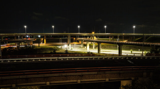 Aerial view of the Westvliet highway intersection at night with illuminated multi-level overpasses and light trails from traffic in Den Haag, Zuid-Holland, Netherlands.