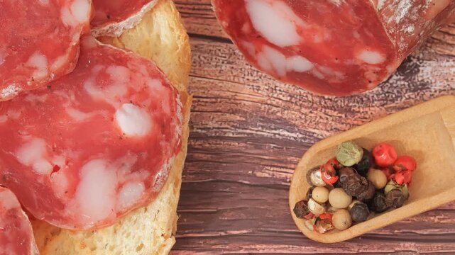 Sliced ​​homemade cured sausage with multicolored peppercorns.